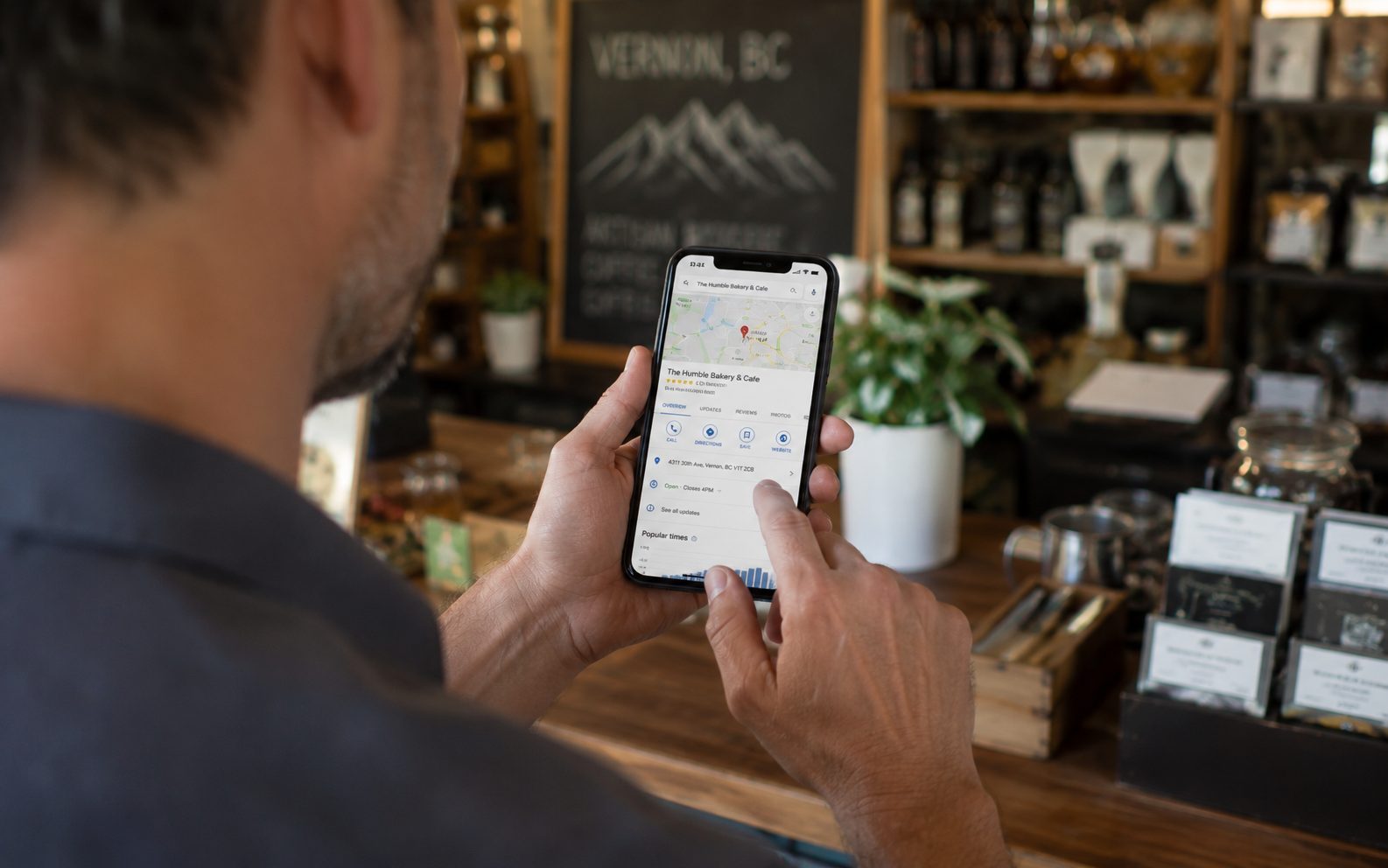Vernon shop owner viewing their Google Business Profile listing on a smartphone behind the counter