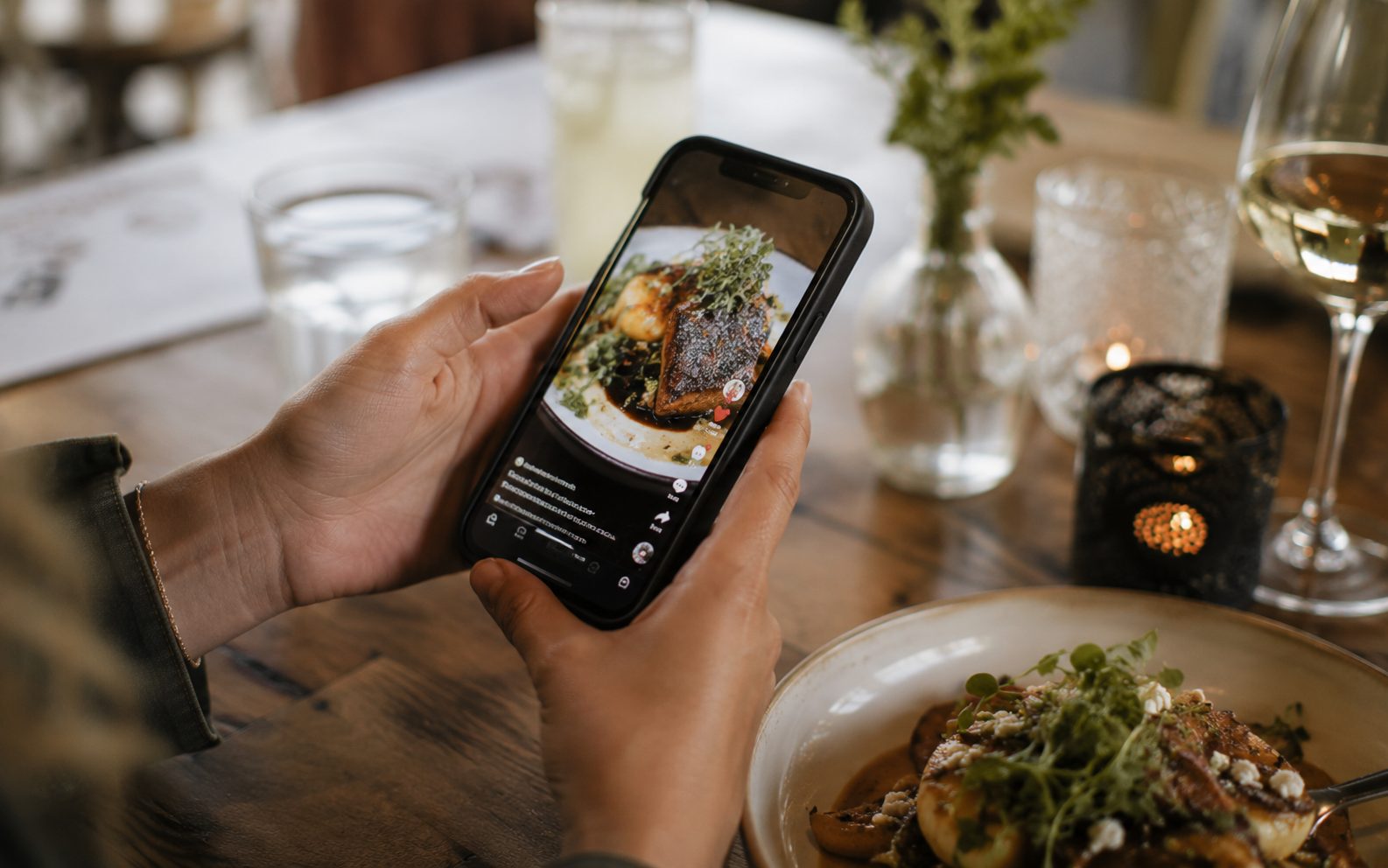 Hands holding a phone watching a short video reel of a local Okanagan restaurant dish