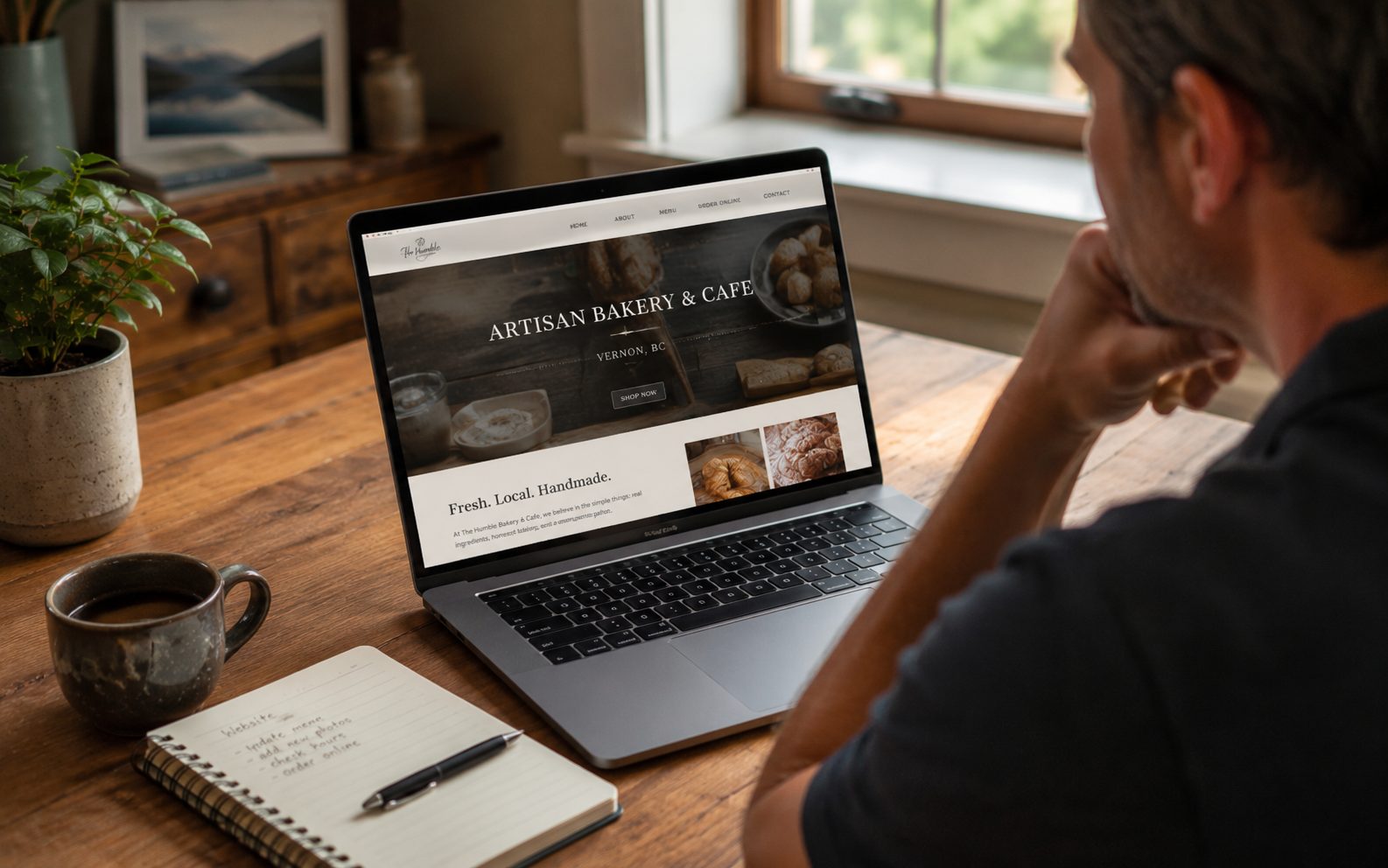 Okanagan business owner reviewing a local website homepage on a laptop at a sunlit desk