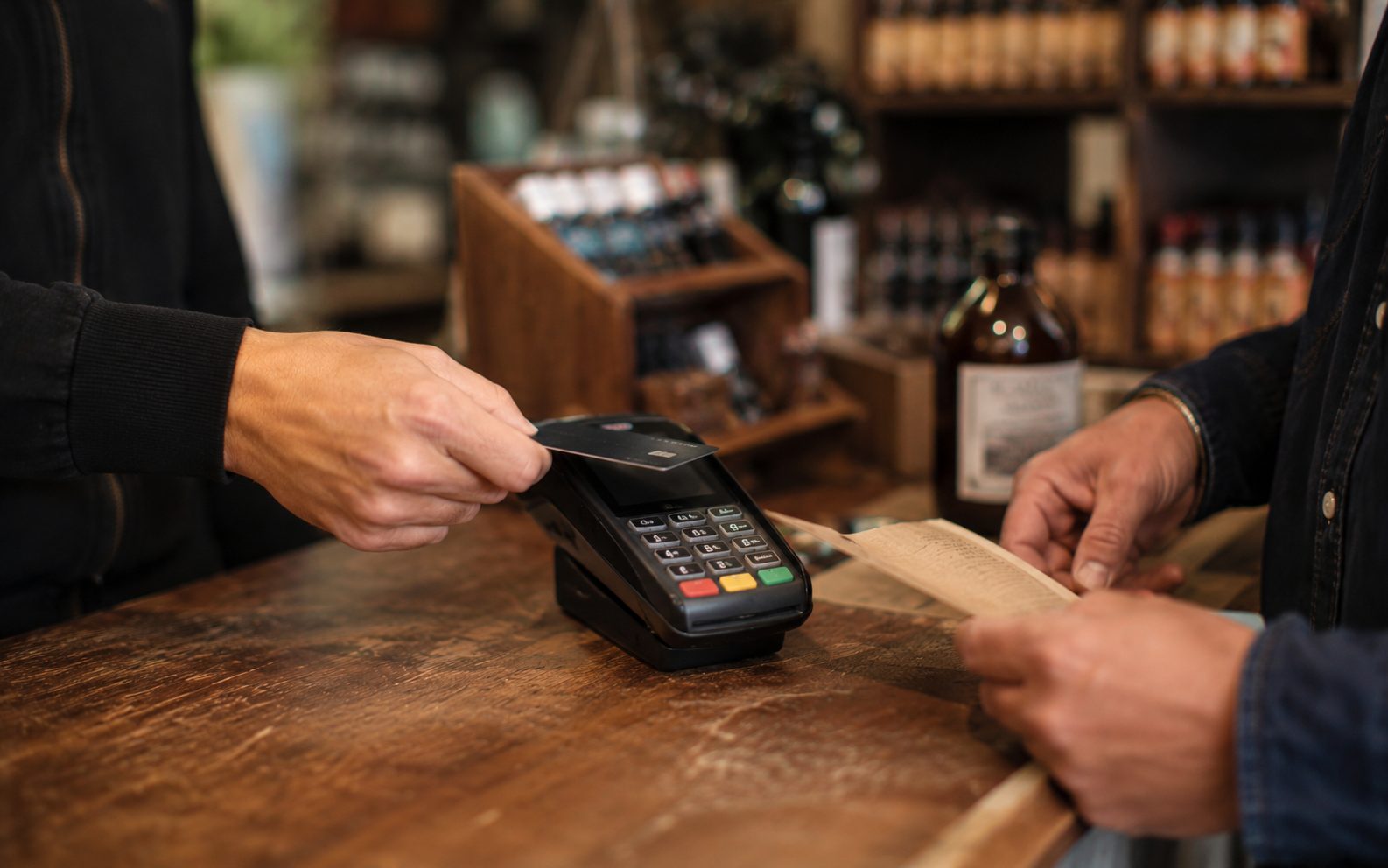 Customer paying at a Vernon BC shop counter with a card machine and receipt